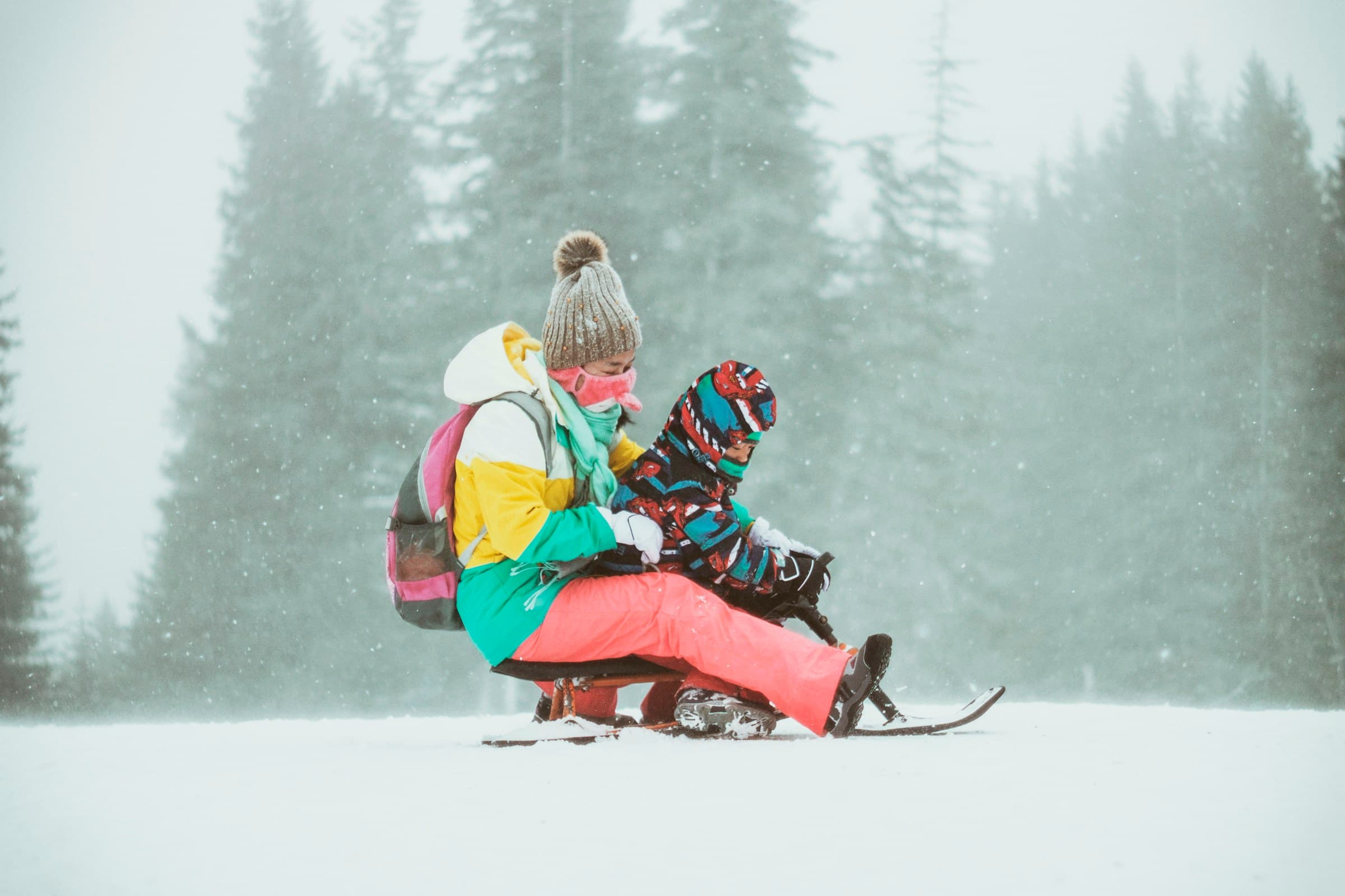 A parent and child enjoying a snowy day on the mountain